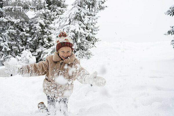 Lächelndes Mädchen  das Spaß mit Schnee im Winterwald hat