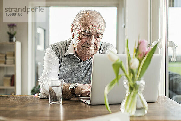 Älterer Mann benutzt Laptop zu Hause