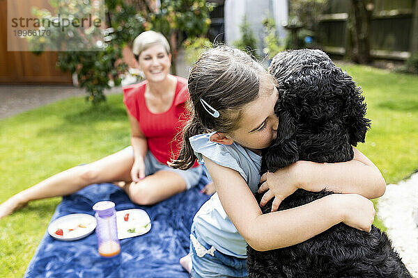 Mädchen umarmt und küsst Hund im Hinterhof