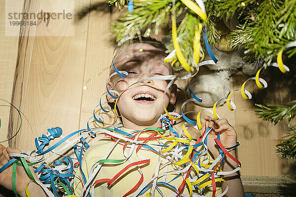 Cheerful boy lying with party poppers at home