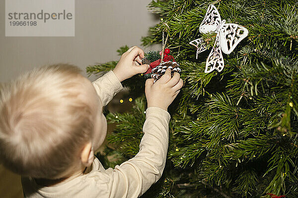 Junge schmückt zu Hause den Weihnachtsbaum