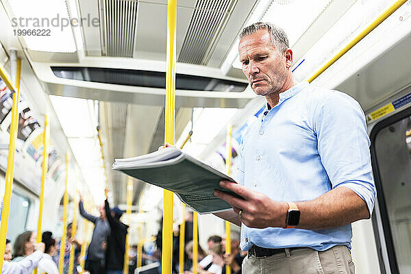 Reifer Geschäftsmann liest Zeitung im Zug