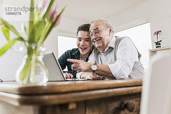 Glücklicher älterer Mann und Enkel unterhalten sich per Videoanruf über Laptop