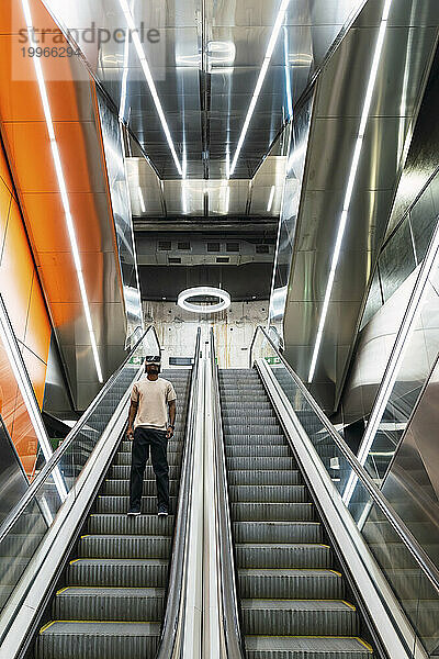 Junger Mann steht auf der Rolltreppe einer U-Bahn-Station