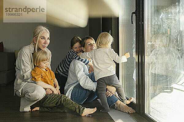 Glückliche Familie  die Spaß daran hat  zu Hause neben der Glastür zu sitzen