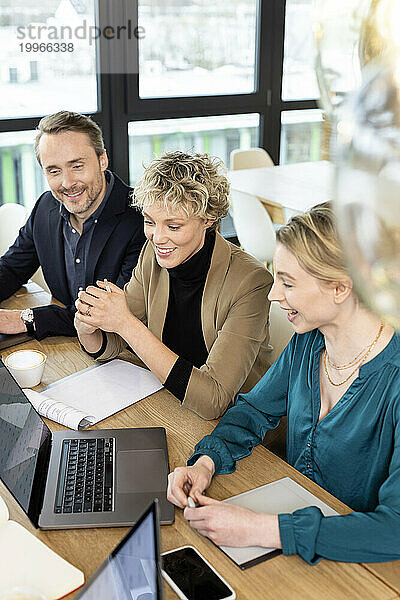 Geschäftskollegen diskutieren am Laptop am Schreibtisch im Büro