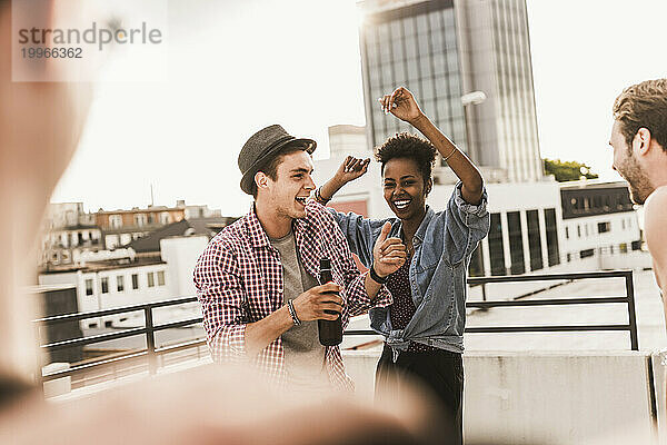Lächelnde Freunde tanzen und genießen auf dem Dach
