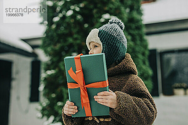 Junge hält grünes Weihnachtsgeschenk in der Hand