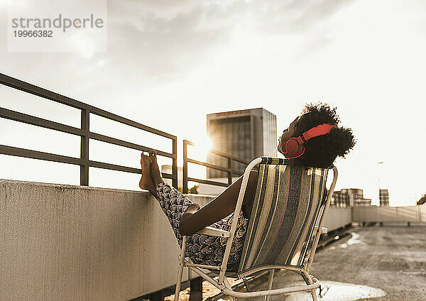Woman wearing headphones and relaxing on rooftop