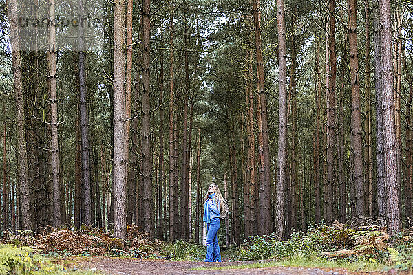 Frau steht mit Rucksack neben Bäumen im Cannock Chase Forest