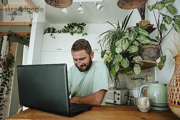 Mann benutzt Laptop in der heimischen Küche