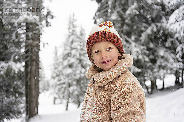 Lächelndes Mädchen mit Strickmütze im Winterwald