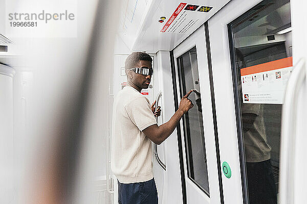 Junger Mann mit Cyberbrille steht im U-Bahn-Zug