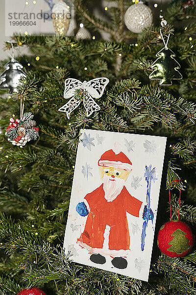 Santa Claus painting hanging on Christmas tree at home