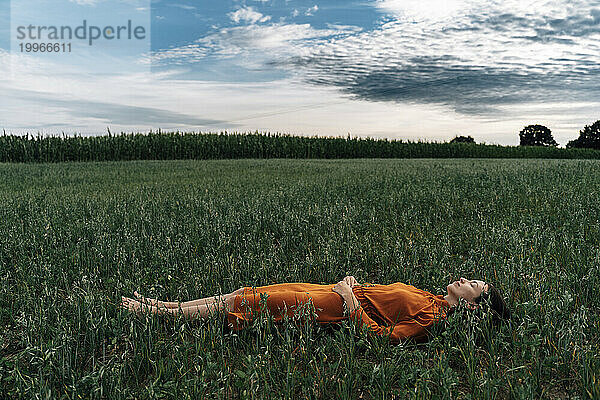 Smiling woman relaxing on crops in field