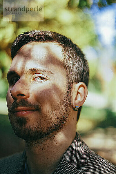 Smiling young man with beard and sunlight on face