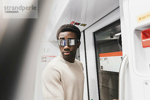 Junger Mann mit Cyberbrille steht im U-Bahn-Zug