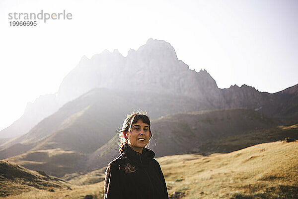 Glückliche Frau  die an einem sonnigen Tag vor dem Berg Kazbegi steht