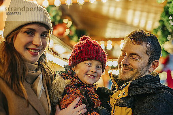 Eltern verbringen ihre Freizeit gemeinsam mit ihrem Sohn auf dem Weihnachtsmarkt