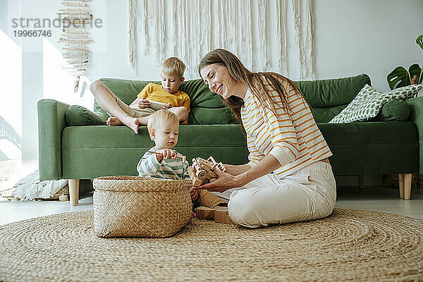 Mutter und Sohn spielen mit Holzspielzeug im Wohnzimmer