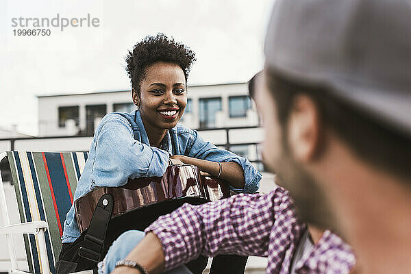 Lächelnde Frau im Gespräch mit einer Freundin auf der Terrasse