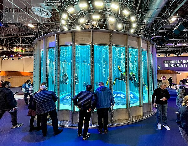 Komplettansicht frontal Totale von mehrere Taucher im Wasser in kreisrunder Tauchturm von Messe boot  am Boden Schriftzug boot Düsseldorf  darüber Lichtinstallation  davor Messebesucher Zuschauer  Düsseldorf  Nordrhein-Westfalen  Deutschland  Europa