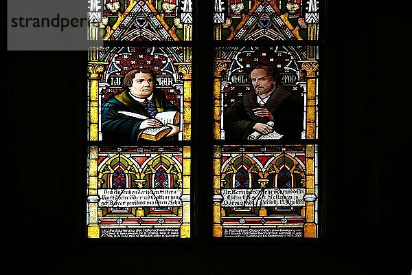 Buntes Kirchenfenster mit Reformatoren Martin Luther mit Schreibfeder und Bibel und Philipp Melanchthon mit Schriftrolle  Reformator  Glasmalerei  Kunsthandwerk  Kirchengeschichte  Berühmtheit  schwarz  Silhouette  Katharinenkirche  Oppenheim  Rheinhessen  Rheinland-Pfalz  Deutschland  Europa