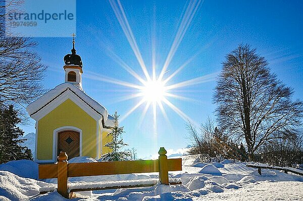 Gegenlichtaufnahme der verschneiten Kapelle Maria auf den Buckelwiesen Werdenfelser Land bei Garmisch in winterlicher Idylle  Bayern  Deutschland  Europa
