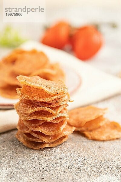 Scheiben von dehydrierten gesalzenen Fleischchips mit Kräutern und Gewürzen auf grauem Betonhintergrund und weißem Textil. Seitenansicht  Nahaufnahme  selektiver Fokus