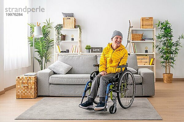 Porträt mit Kopiervorlage eines glücklichen behinderten Mannes in warmer Kleidung im Rollstuhl im Wohnzimmer
