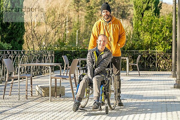 Porträt mit Kopiervorlage eines glücklichen behinderten Mannes und seiner Freunde in einem sonnigen Stadtpark