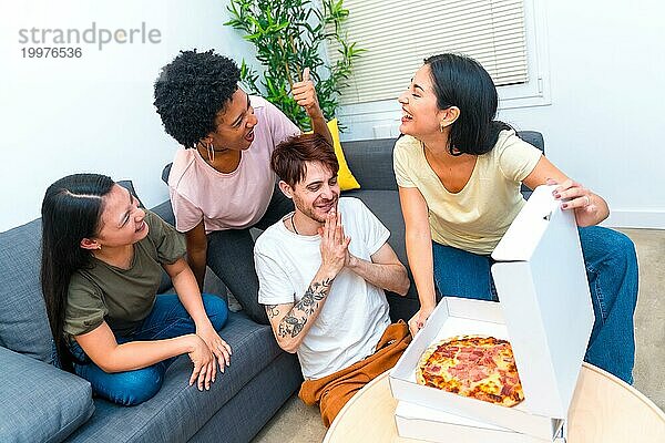 Draufsicht auf eine Gruppe hungriger multiethnischer Freunde  die eine gelieferte Pizza öffnen