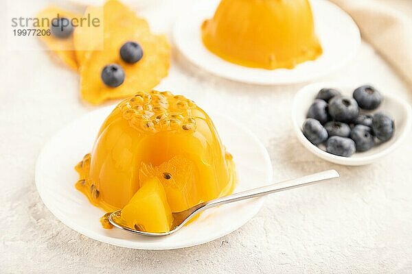 Mango und Maracuja Gelee mit Heidelbeeren auf grauem Betonhintergrund und Leinentextil. Seitenansicht  Nahaufnahme  selektiver Fokus