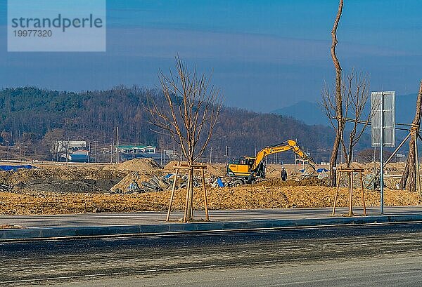 Ein nicht identifizierter Mann mit blauem Schutzhelm steht vor einem Bagger  der auf einer Baustelle Schmutz und Müll bewegt. Nur zur redaktionellen Verwendung  Südkorea  Daejeonn  Südkorea  Asien