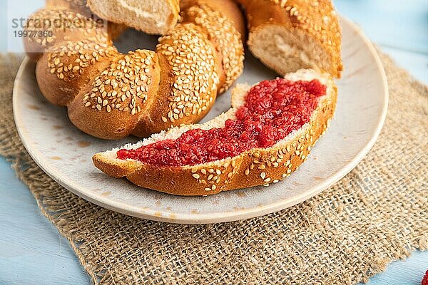 Hausgemachte süße Brötchen mit Himbeermarmelade und eine Tasse Kaffee auf einem blauen hölzernen Hintergrund und Leinenstoff. Seitenansicht  Nahaufnahme  selektiver Fokus