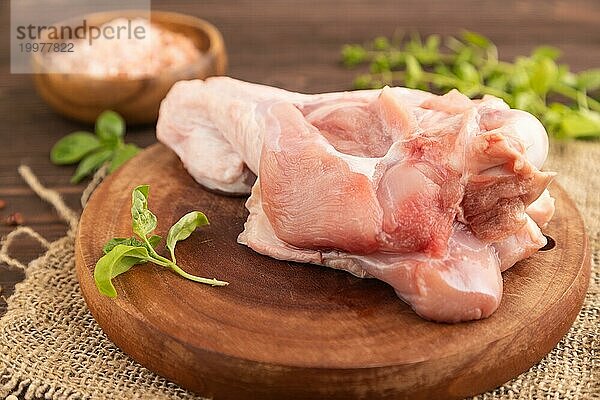 Roher Putenflügel mit Kräutern und Gewürzen auf einem hölzernen Schneidebrett auf einem braunen Holzhintergrund und Leinenstoff. Seitenansicht  Nahaufnahme  selektiver Fokus