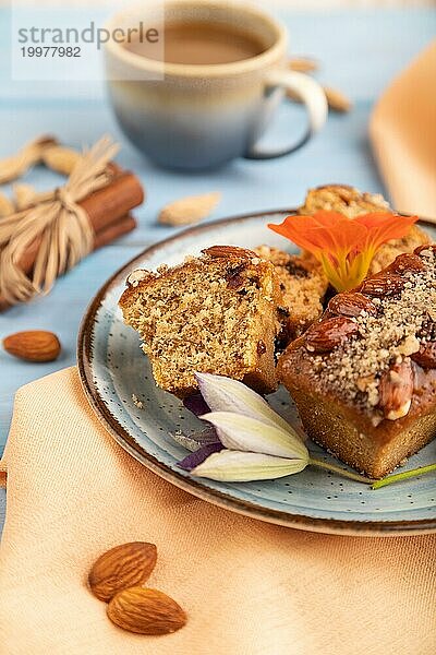 Karamell und Mandelkuchen mit Tasse Kaffee auf blauem Holzhintergrund und orangefarbenem Leinenstoff. Seitenansicht  Nahaufnahme  selektiver Fokus