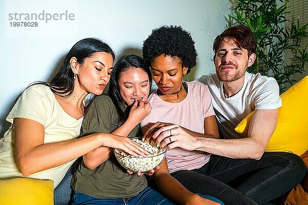 Freunde genießen Popcorn bei einem Filmabend auf dem Sofa zu Hause