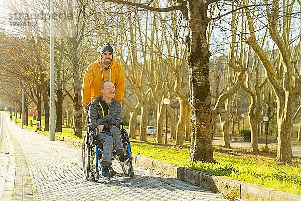 Behinderter Mann und Freund auf einem Weg in einem Park an einem sonnigen Wintertag