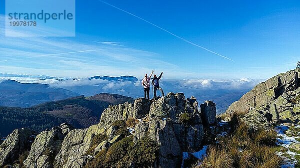 Zwei Männer erreichen beim Trekking den Gipfel eines Berges