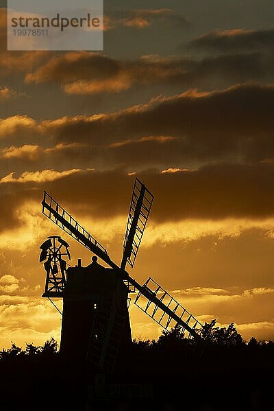 Windmühle als Silhouette bei Sonnenuntergang mit rotem Himmel und Wolken dahinter  Cley next to the sea  Norfolk  England  Großbritannien  Europa