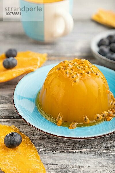 Mango und Maracuja Gelee mit Heidelbeeren auf grauem Holzhintergrund. Seitenansicht  Nahaufnahme  selektiver Fokus