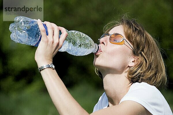 Junge Frau trinkt aus einer Wasserflasche