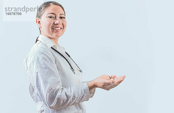 Schöne lächelnde Ärztin zeigt eine Anzeige mit Handflächen. Glückliche Ärztin präsentiert etwas mit Palmen
