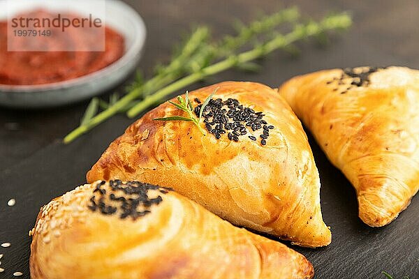 Hausgemachte asiatisches Gebäck Samosa auf schwarzem Beton Hintergrund. Seitenansicht  selektiver Fokus