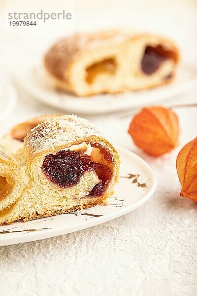 Hausgemachtes süßes Brötchen mit Aprikosenmarmelade und Tasse Kaffee auf grauem Betonhintergrund. Seitenansicht  Nahaufnahme  selektiver Fokus