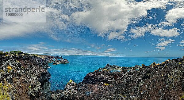 Dramatischer Blick auf eine von vulkanischen Felsen gesäumte Küstenlinie unter einem heiteren Himmel  Lavafelsen Küstenwanderweg Ponta da Iiha  Calhau  Westküste  Pico  Azoren