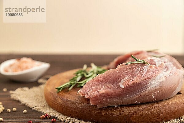 Rohes Schweinefleisch mit Kräutern und Gewürzen auf einem Holzschneidebrett auf einem braunen Holzhintergrund. Seitenansicht  Nahaufnahme  selektiver Fokus