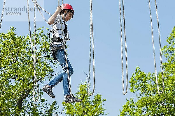 Junges Mädchen im Kletterpark  klettern  Aktion  Sicherheit  Sicherung  Absichern  Sicherungsseil  Sicherrungstechnik  Sicherungshaken  Mut  mutig  Freizeit  Hobby  Höhe  Höhenangst  Überwindung  Sport