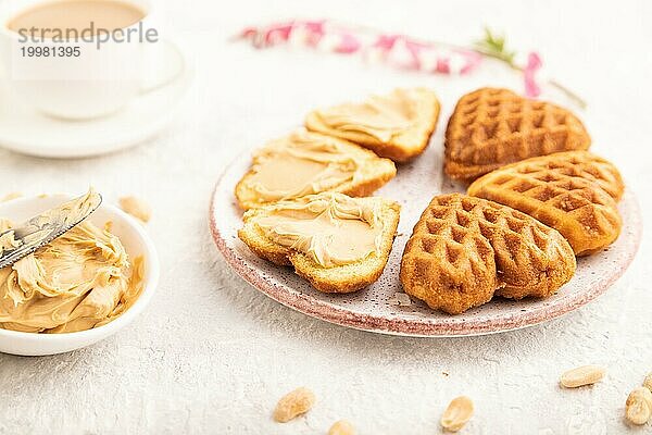 Hausgemachte Waffel mit Erdnussbutter und Tasse Kaffee auf einem grauen Betonhintergrund. Seitenansicht  Nahaufnahme  selektiver Fokus